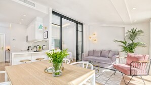 A modern living space with a wooden dining table, a sofa, and a pink chair. - Atico Sebastian Souviron - Penthouse in Malaga (Málaga)