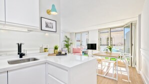 A modern kitchen with white cabinetry, a central island, and a dining area with a table and chairs. - Atico Sebastian Souviron - Penthouse in Malaga (Málaga)