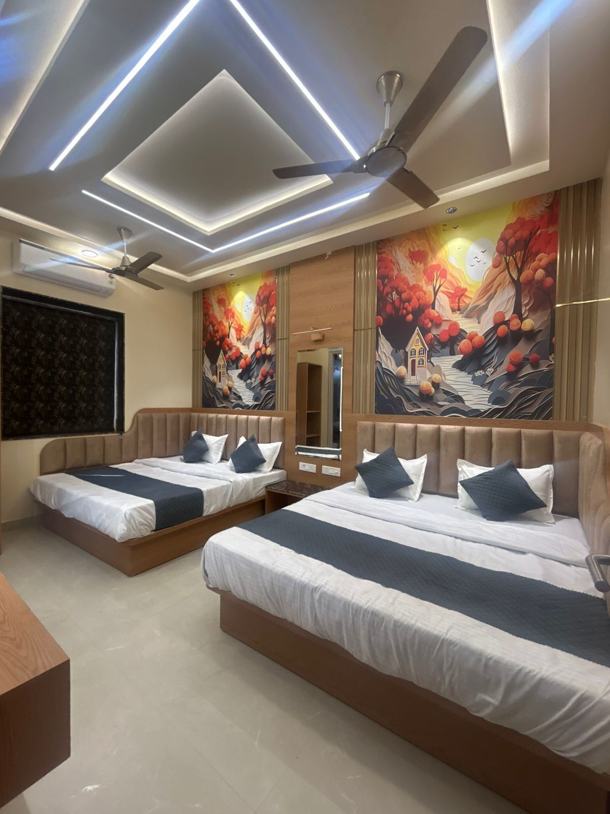 A hotel room with two beds, a ceiling fan, recessed lighting, and a mural on the wall.