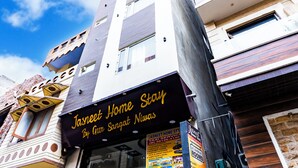 A building with a sign reading "Jasneet Home Stay By Gur Sangat Niwas" and a poster advertising various services. - jasneet home stay (Amritsar)