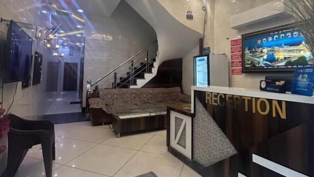 A modern reception area with a chandelier, a reception desk, and a staircase leading to upper floors. - jasneet home stay (Amritsar)