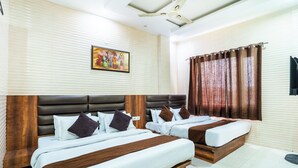 A hotel room with two beds, a ceiling fan, a painting on the wall, and a window with curtains. - jasneet home stay (Amritsar)