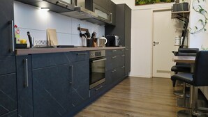 Une cuisine moderne avec des meubles de couleur sombre, des appareils en acier inoxydable et un plan de travail en bois.