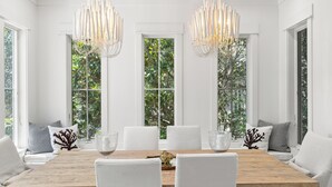 A dining room with a wooden table, white chairs, and two chandeliers. - Prime Seagrove Location | Private Pool, Bikes, Porches, Steps to Beach Access (Santa Rosa Beach)