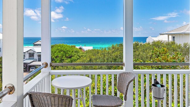 A balcony with a view of the ocean, white railings, wicker chairs, and a small table. - Prime Seagrove Location | Private Pool, Bikes, Porches, Steps to Beach Access (Santa Rosa Beach)