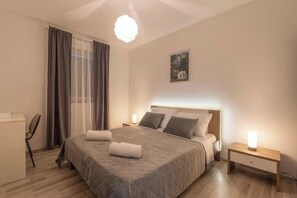 Une chambre bien rangée, avec un lit, des tables de chevet, un bureau et une chaise.