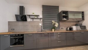 A modern kitchen with grey cabinetry, a built-in oven, a microwave, and a coffee maker. - Holiday home Galižana (Galižana)