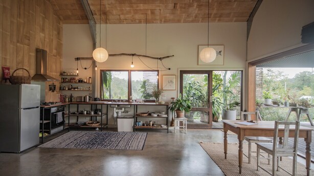 Una cocina amplia con una isla grande, armarios de madera y vistas al exterior a través de ventanas panorámicas.