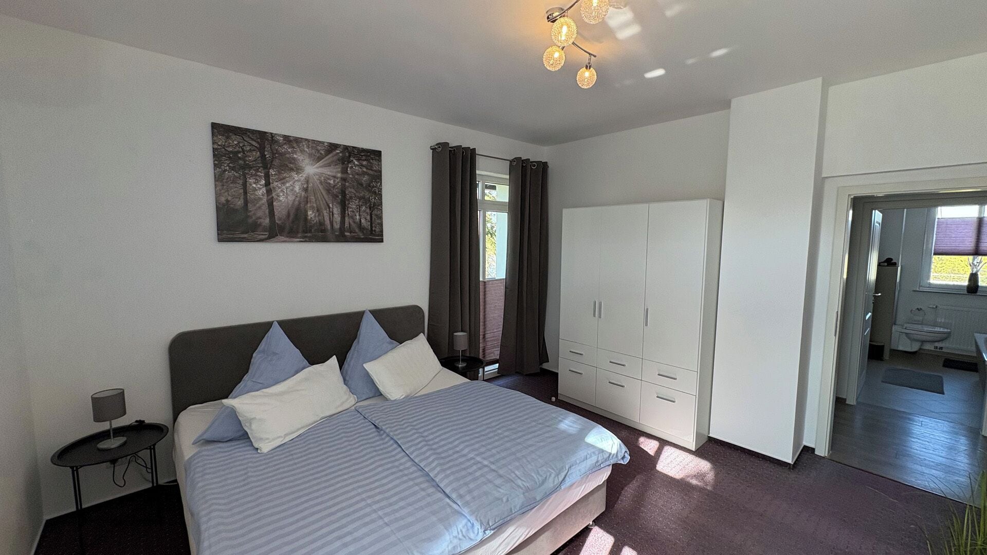 Une chambre à coucher avec un lit, une armoire, une table de chevet et un tableau au mur.