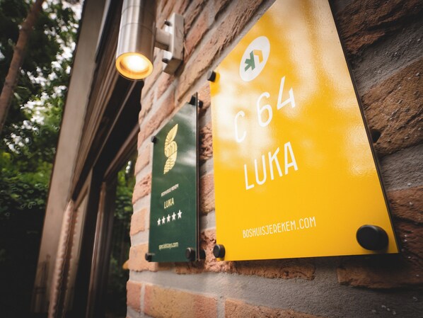 Un muro de ladrillo con dos placas, una verde y otra amarilla, con texto y un logotipo.