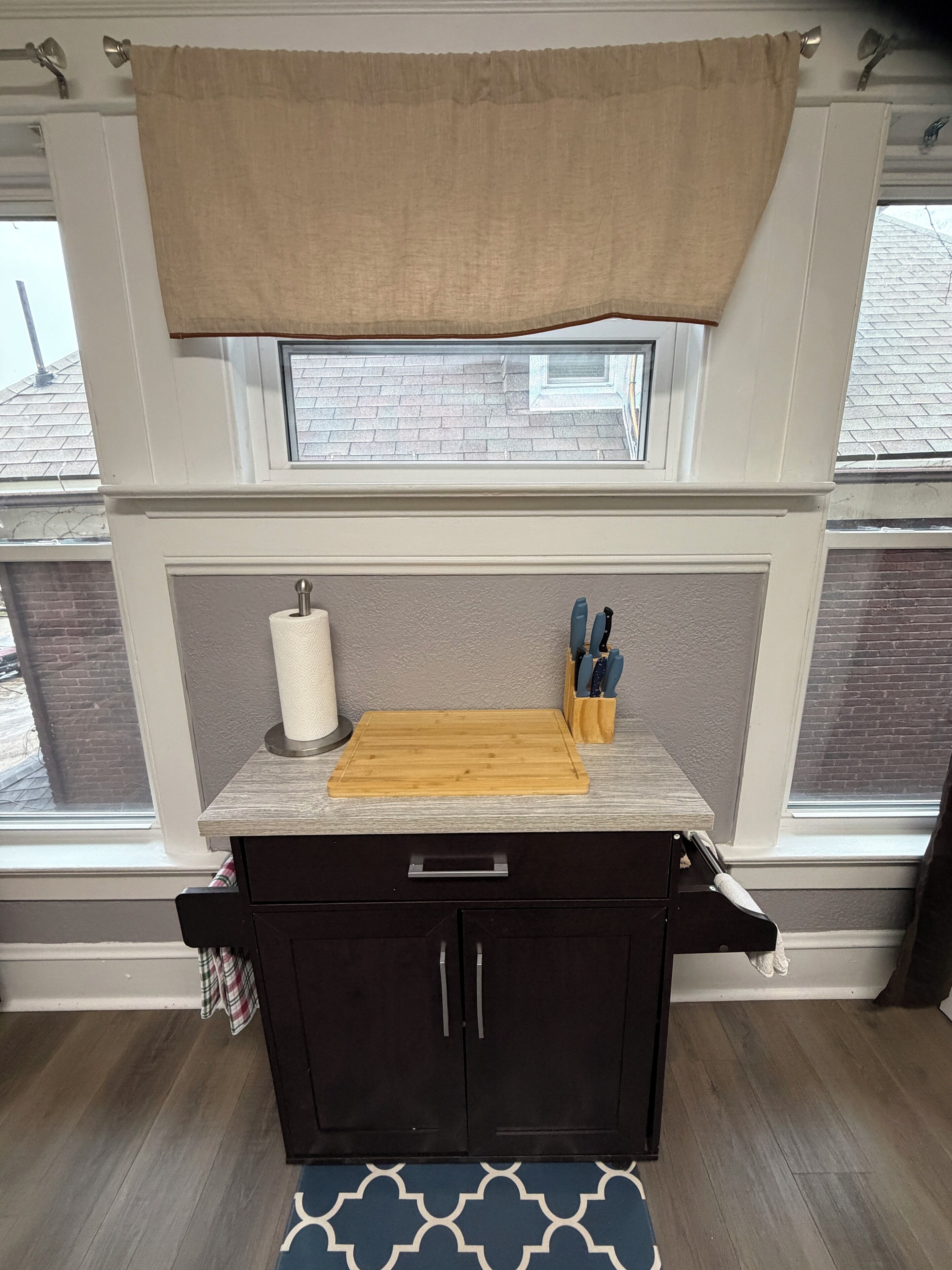 A kitchen with a wooden countertop, a cutting board, a paper towel holder, and a knife block.