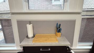 A kitchen with a wooden countertop, a cutting board, a paper towel holder, and a knife block.