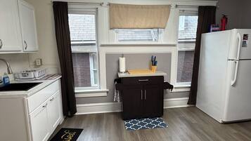 A compact kitchen with white cabinets, a black countertop, and a white refrigerator.