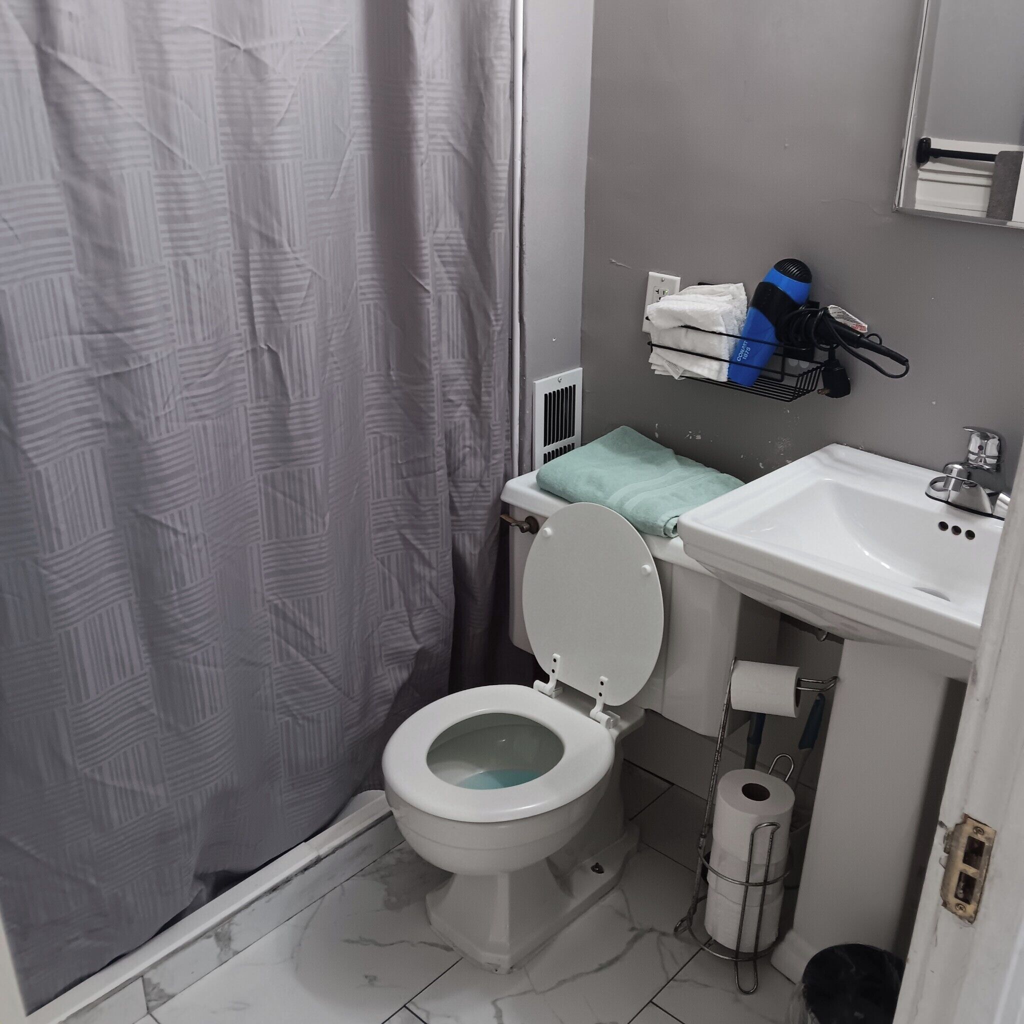 Une salle de bain équipée de toilettes, d’un lavabo et d’un rideau de douche.