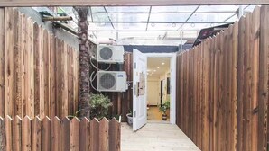 A narrow wooden pathway leading to a room with a door, surrounded by wooden walls and air conditioning units. - Shanghai Hills&Zinn Changle road Homestay (Shanghai)