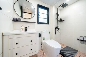 A bathroom with a white sink, mirror, toilet, and shower.