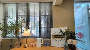 A reception desk with a lamp, a Freepik poster, water bottles, and a potted plant. - Shanghai Hills&Zinn Changle road Homestay (Shanghai)