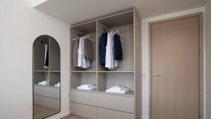 A walk-in closet with open shelves, a hanging rod, and a mirror. - The Yellow Corporate Suite (Milton Keynes)