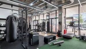 Un gimnasio con equipo de levantamiento de pesas, cintas de correr y colchonetas de ejercicio.