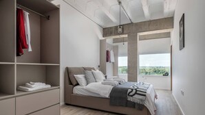 Un dormitorio moderno con una cama grande, estanterías empotradas y vistas al verdor a través de un amplio ventanal.