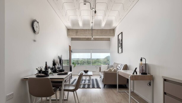 Un espacio habitable moderno y de planta abierta, con zona de comedor, sofá y escritorio.