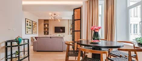 A modern living room with a sofa, dining table, chairs, and a TV.