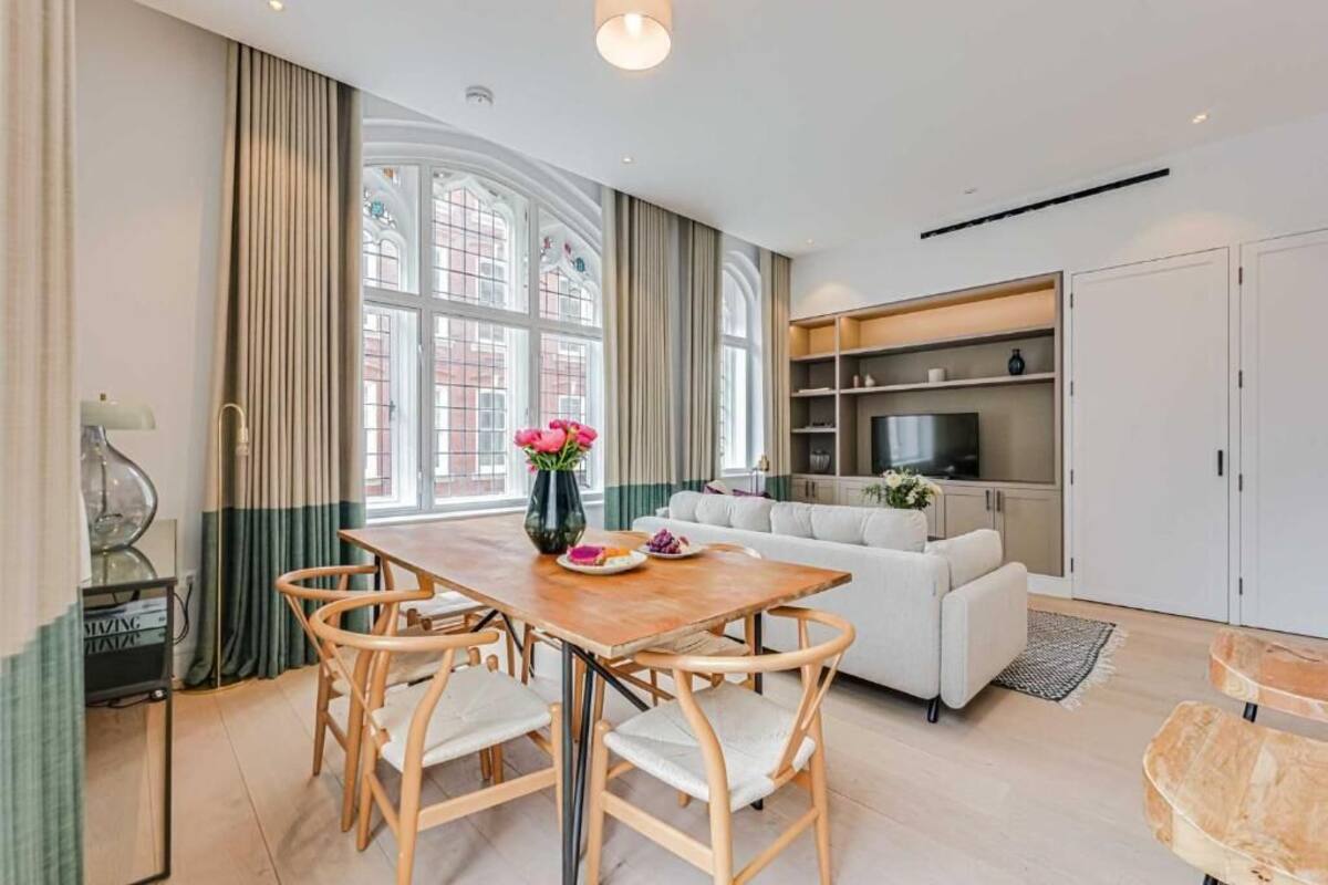 Un salon moderne comprenant une table à manger, des chaises, un canapé et un téléviseur.