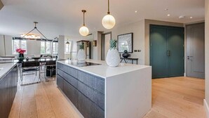 Een moderne keuken met een centraal eiland, hanglampen en uitzicht op de eetruimte.
