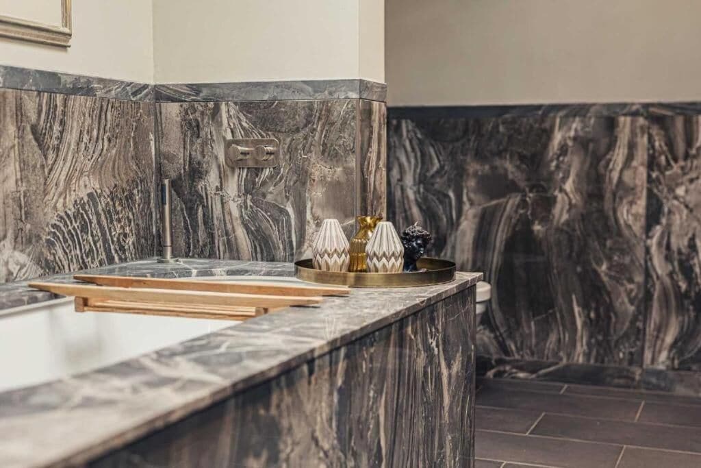 Eine Küchenarbeitsplatte aus Marmor mit einem Wasserhahn, einer Ablage mit Dekoration und einer Marmor-Spritzschutzwand.