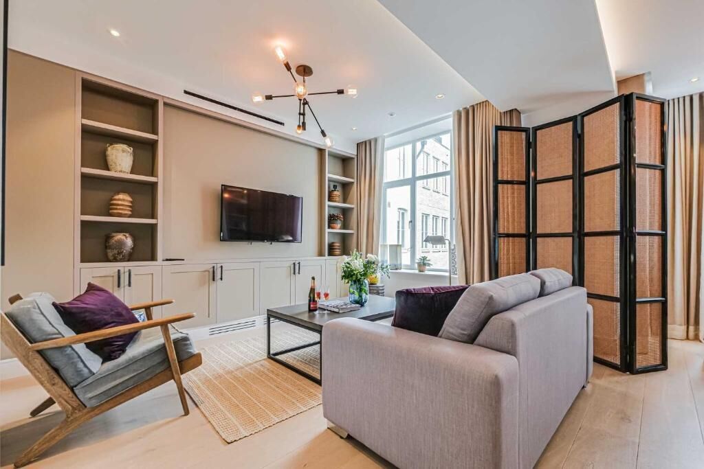A modern living room with a sofa, a coffee table, a TV, and a bookshelf.