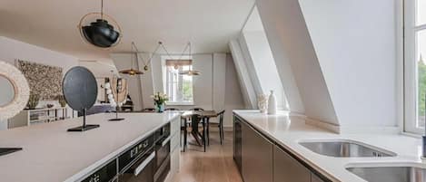 A modern kitchen with a central island, stainless steel appliances, and a large window providing natural light.
