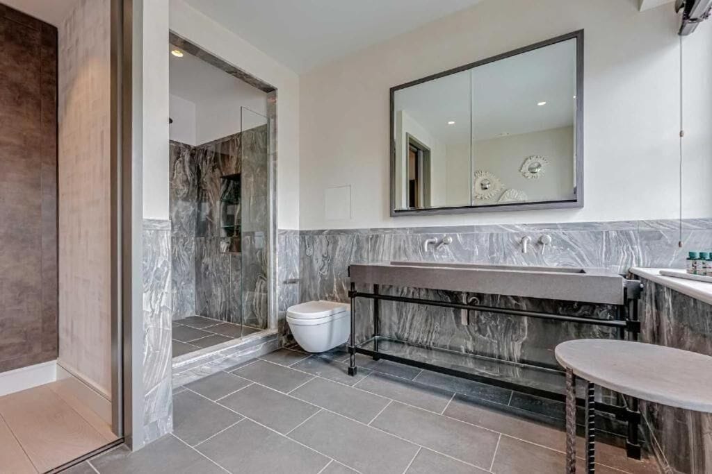 A bathroom with a marble vanity, a large mirror, and a shower area.