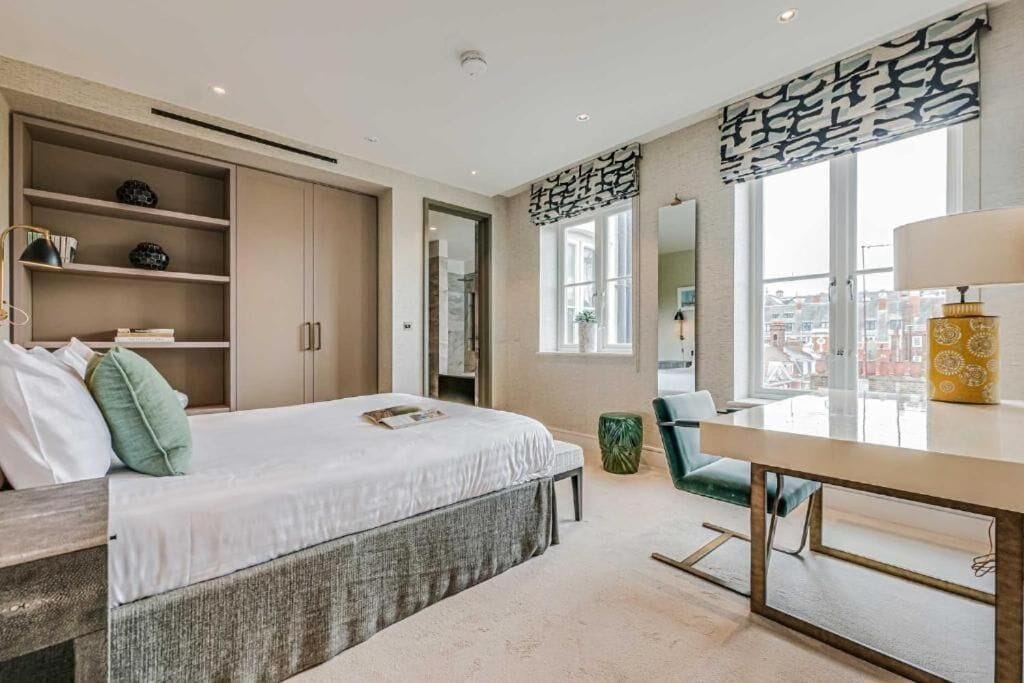 Une chambre à coucher moderne, équipée d’un lit, d’un bureau, d’une chaise et d’une grande fenêtre.