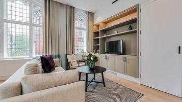 A living room with a sofa, a round coffee table, a TV, and a bookshelf.