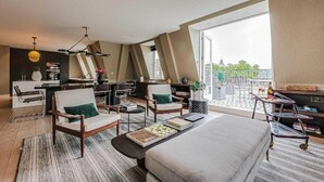 Een moderne hotelkamer met een groot bed, twee fauteuils, een bureau en een balkon met uitzicht.