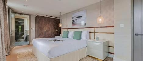 A modern bedroom with a large bed, a nightstand, a wall-mounted lamp, and a sliding glass door leading to a balcony.