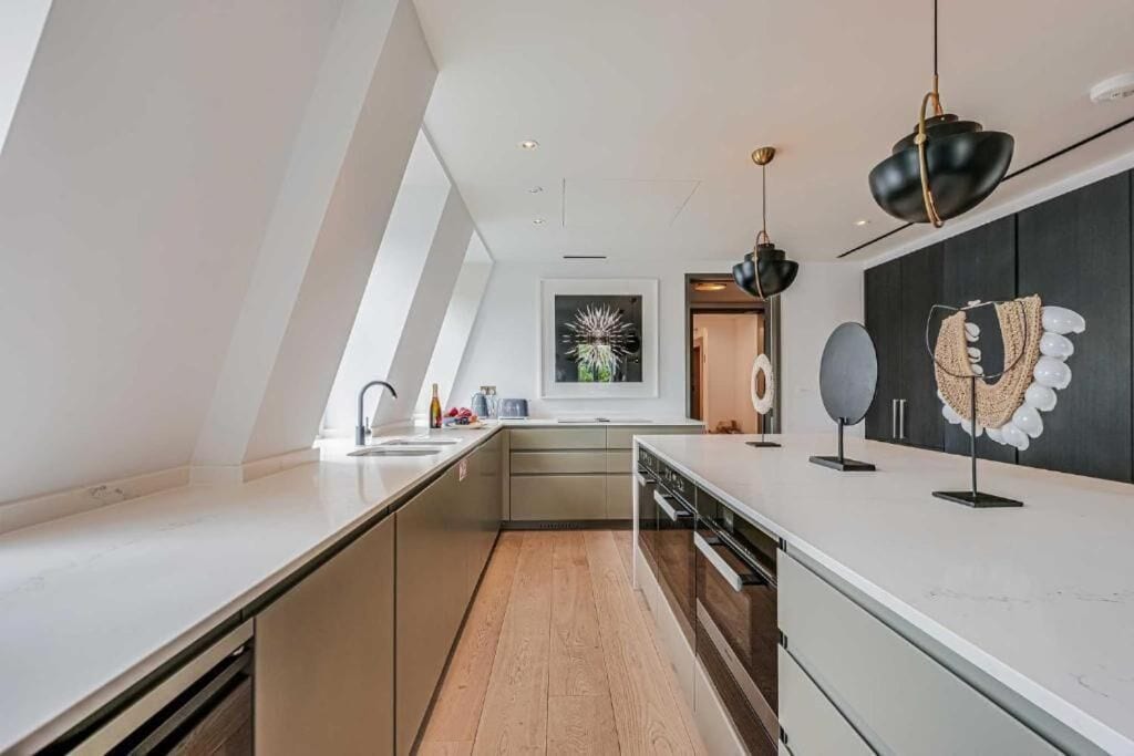 Una cocina moderna con encimera blanca, horno empotrado y una lámpara colgante.