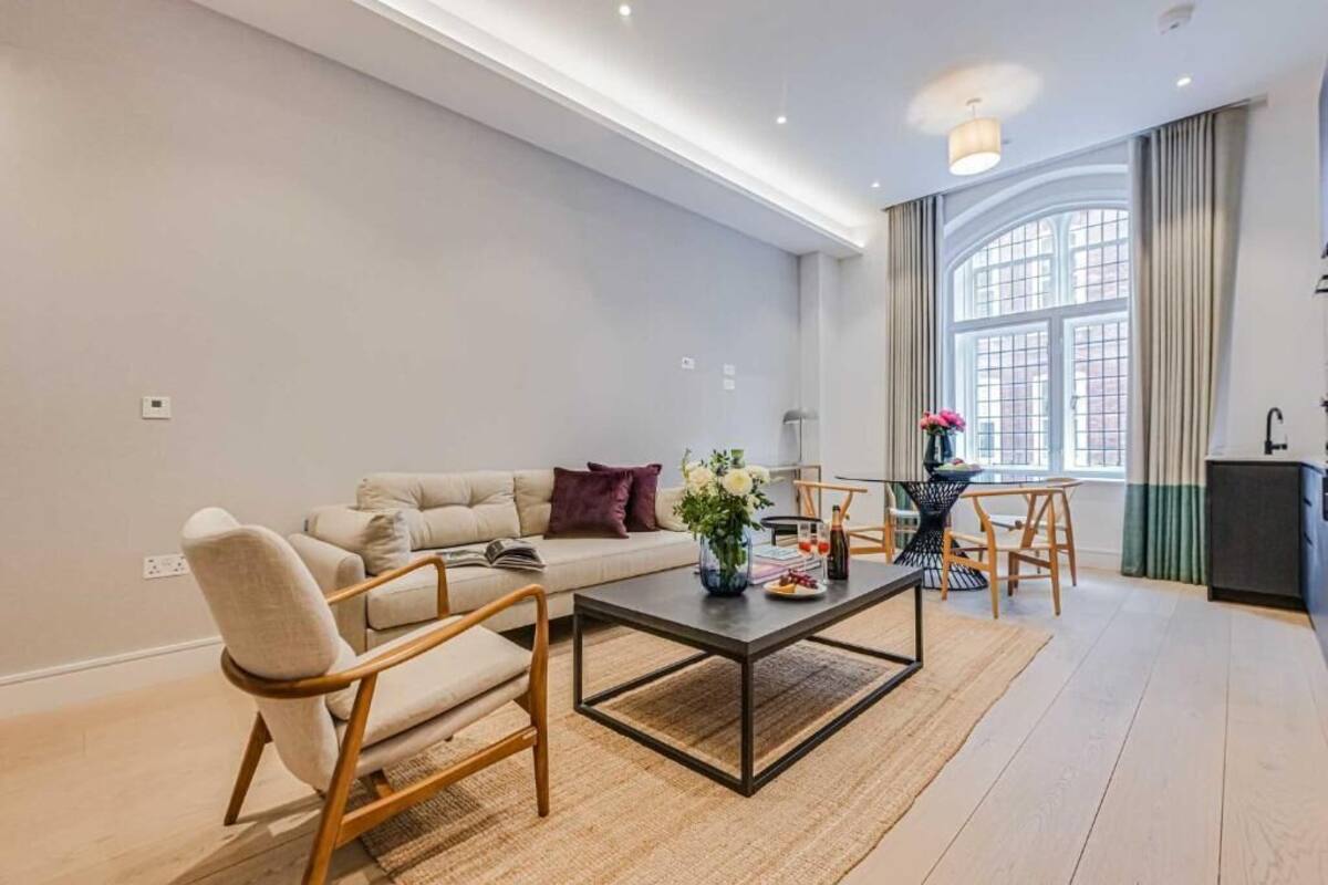 Un salon moderne comprenant un canapé, un fauteuil, une table basse et un coin repas avec des chaises.