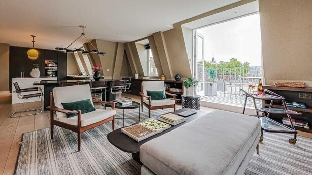 Een moderne hotelkamer met een groot bed, zithoek, eettafel en een balkon met uitzicht.