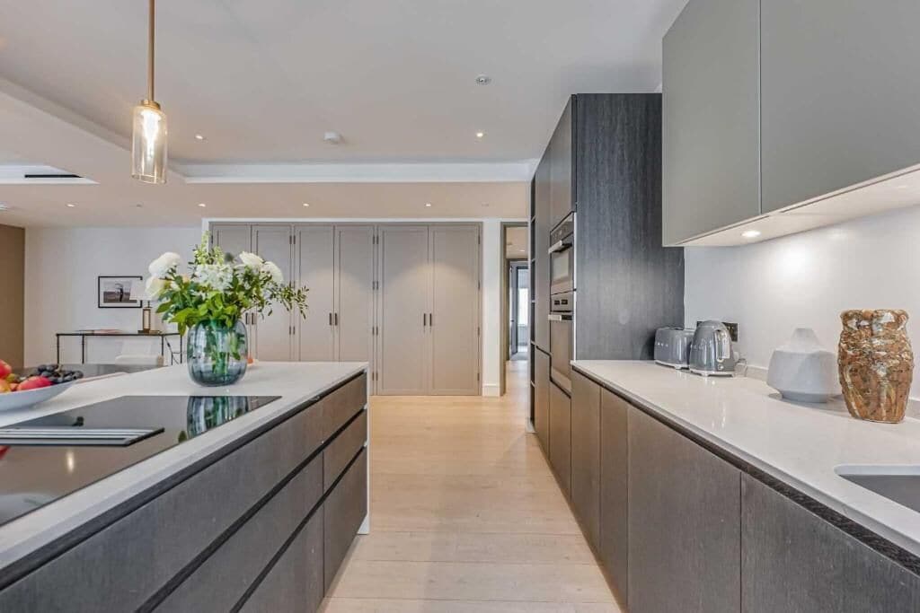 A modern kitchen with dark cabinetry, a central island, and a hanging light fixture.