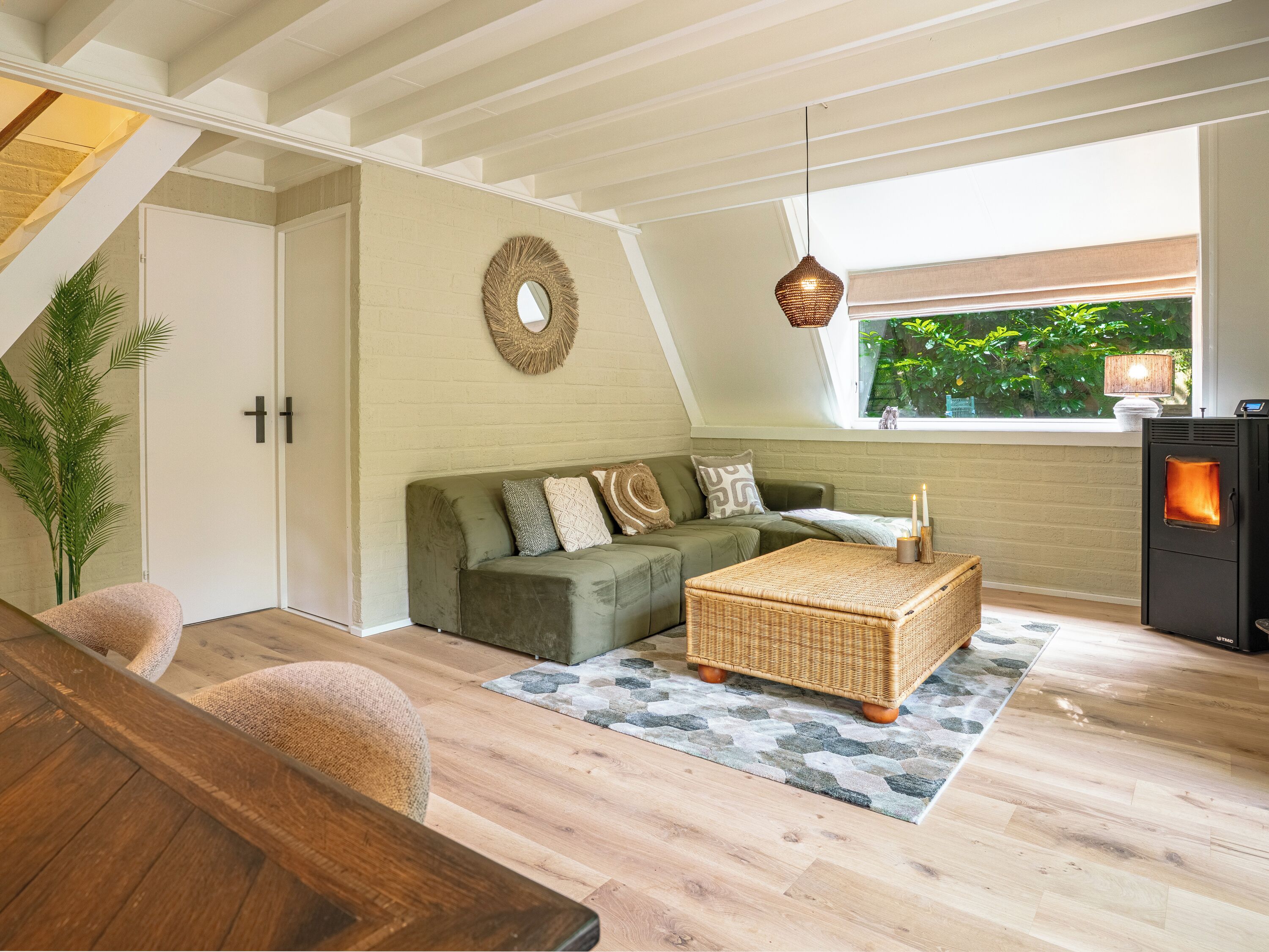 A cozy living room with a green sofa, a wicker coffee table, and a wood-burning stove.