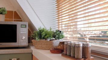 Una cocina con microondas, especiero y plantas en macetas sobre la encimera.
