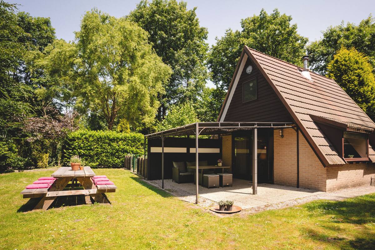 A rustic cabin with a covered patio, a picnic table, and a small garden area.
