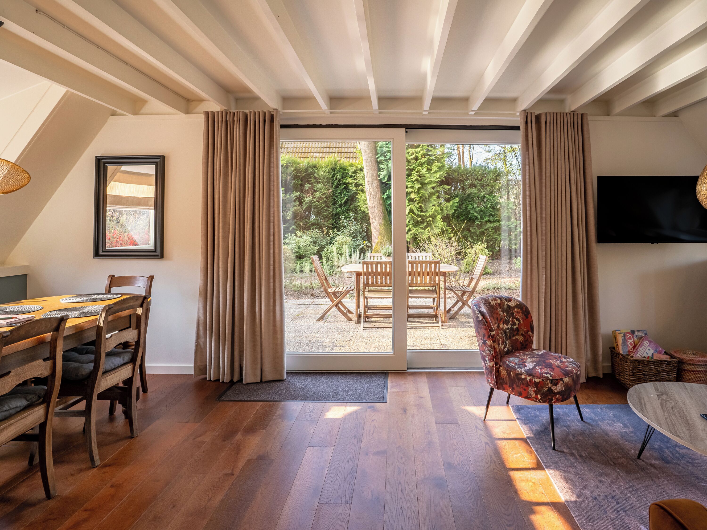 Ein geräumiges Zimmer mit Essbereich, einer gemütlichen Sitzecke mit Sofa und Sessel sowie einer großen Glasschiebetür, die auf eine Außenpatio führt.