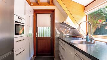 Una cocina compacta con un refrigerador Bosch, horno y una puerta de madera.