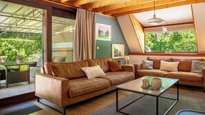A modern living room with a brown leather sofa, a glass coffee table, and a wooden ceiling. - Boshuisje Rekem Three-Bedroom Houses (Lanaken)