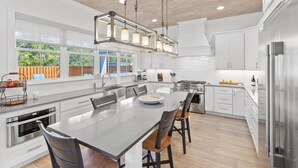 A modern kitchen with a large island, stainless steel appliances, and a hanging light fixture. - 5BR Home w/ private heated pool, golf cart, near 30A! (Santa Rosa Beach)