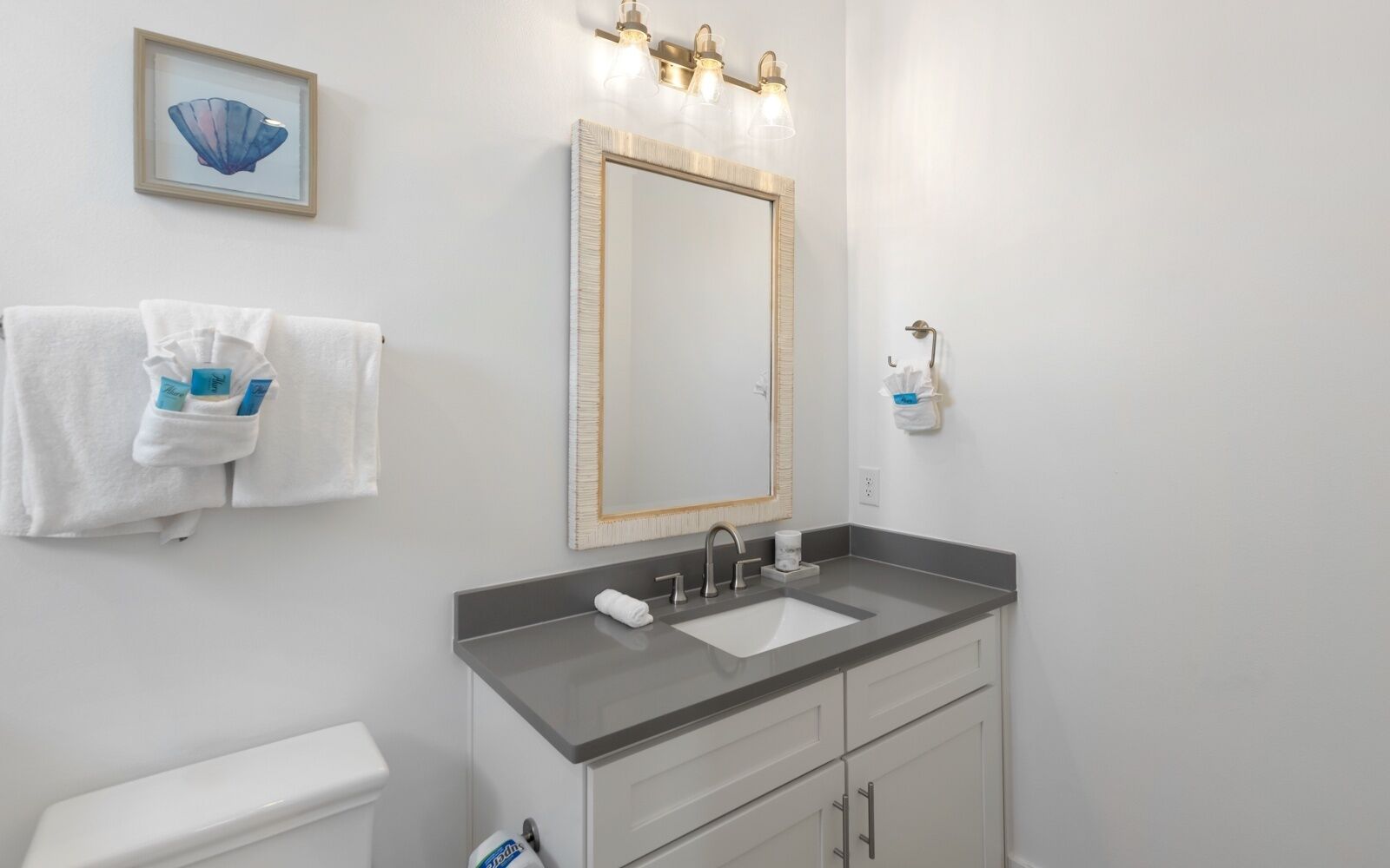 A bathroom with a white sink, a mirror with a gold frame, and a towel rack with white towels.
