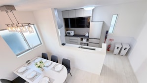 Cozinha moderna com armários brancos, micro-ondas e pia. Possui um espaço de jantar com uma mesa posta para quatro e cadeiras pretas.