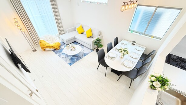 Um apartamento moderno com área de jantar, um sofá com almofadas amarelas, uma televisão e uma janela grande.